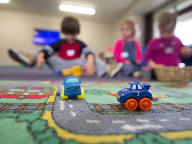 A group of children playing with toys on the floor.