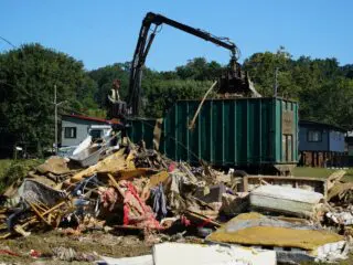 A claw operator scoops up debris from homes demolished following Hurricane Helene in Old Fort, North Carolina, on Thursday, Sept. 11, 2025