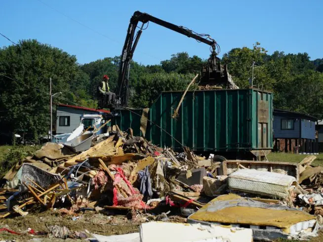 A claw operator scoops up debris from homes demolished following Hurricane Helene in Old Fort, North Carolina, on Thursday, Sept. 11, 2025